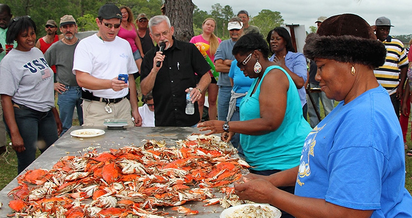 People crowded around a table of cooked blue crabs