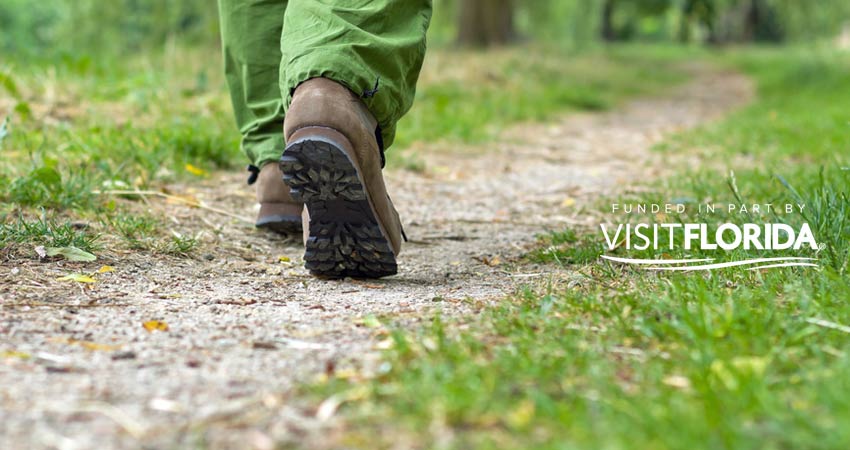 Closeup of hiking boots walking down trail with visit florida logo