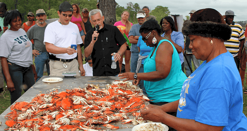 Group of people surrounding table of cooked blue crabs