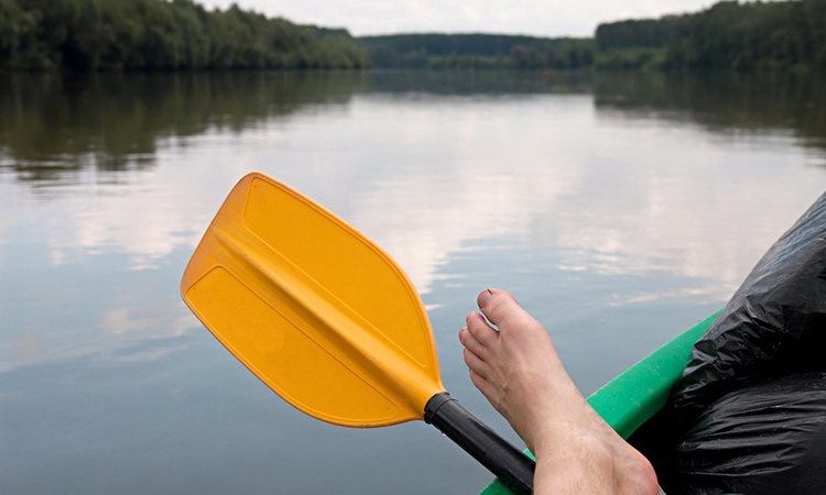 Foot and paddle hanging off kayak