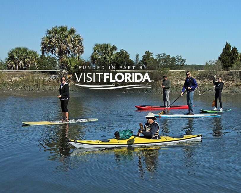 People kayaking and paddle boarding with visit florida logo